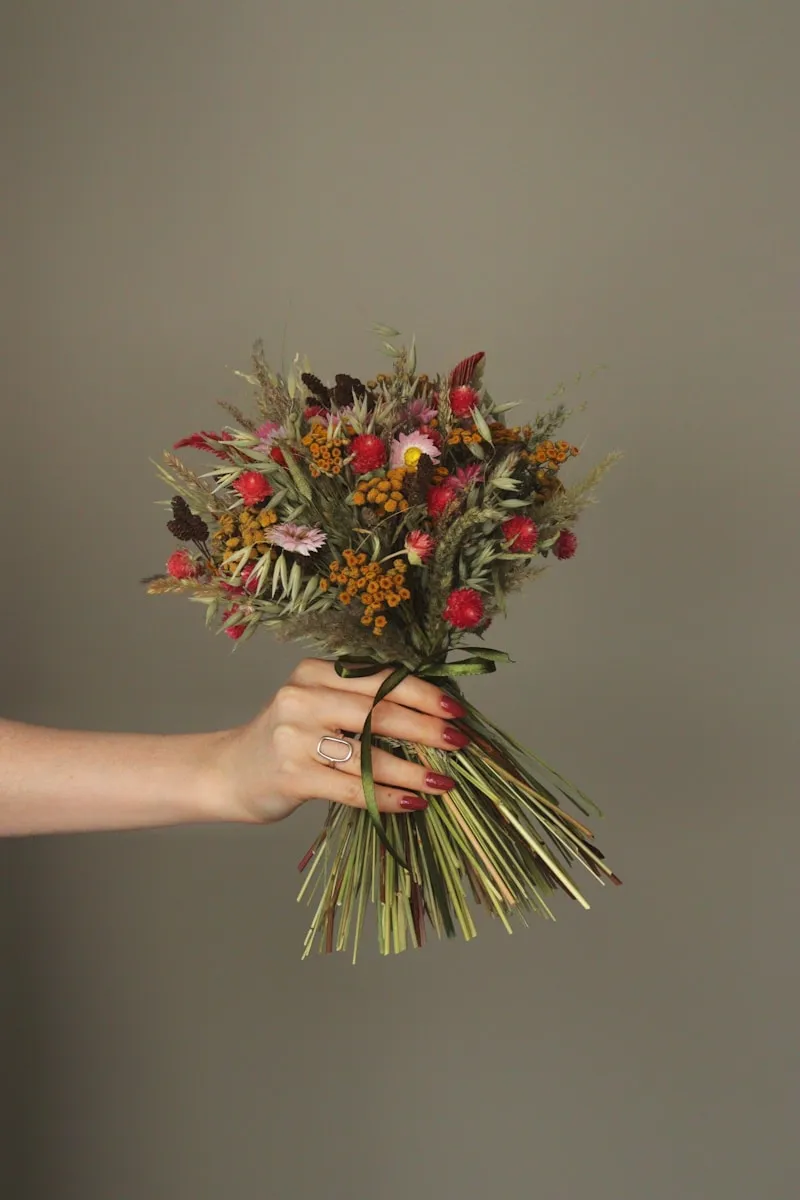 Florist hands tying a hand-bound bouquet with ribbon